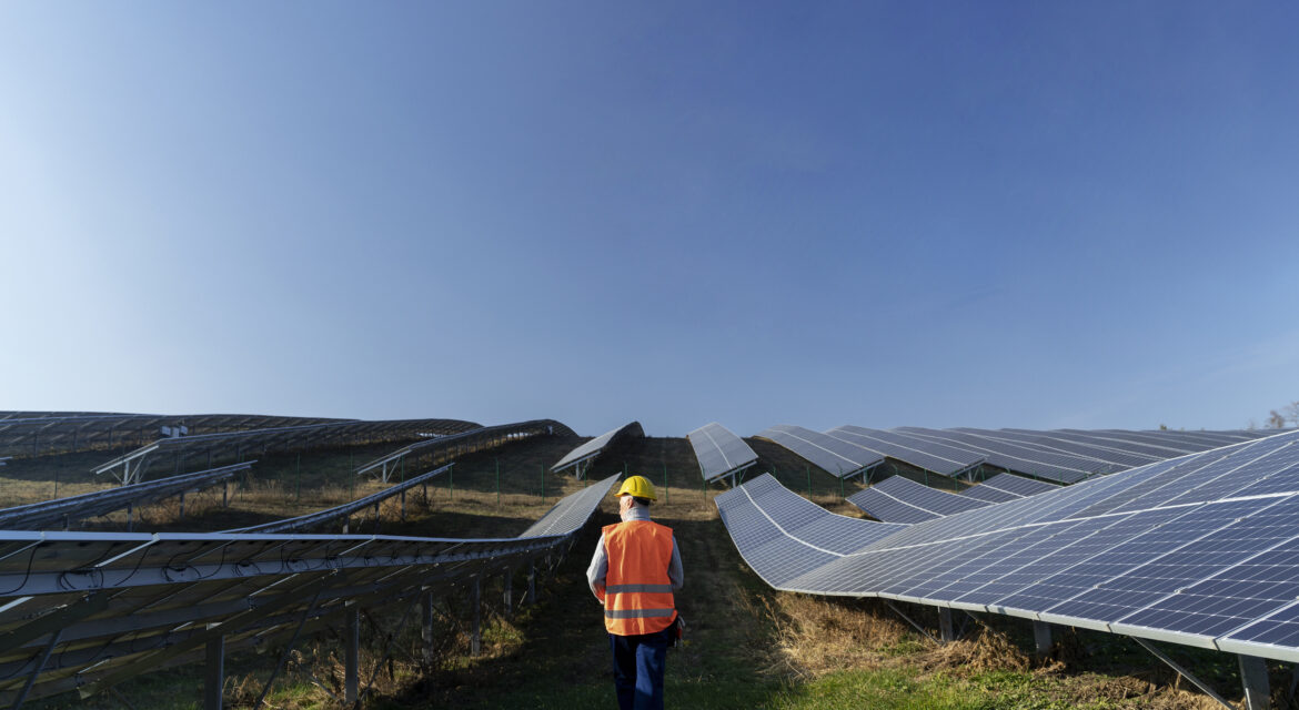An engineer walking in between a row of solar farm