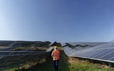 An engineer walking in between a row of solar farm