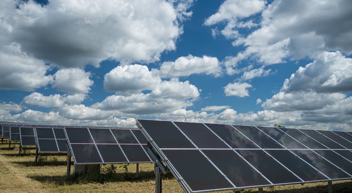 Solar panels in an open space under the sky full of clouds