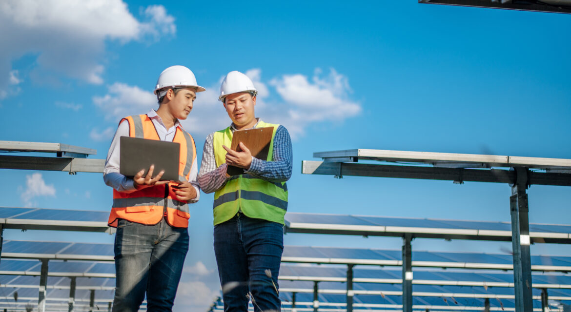 Two men in safety vests talking in the middle of a solar farm