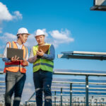 Two men in safety vests talking in the middle of a solar farm