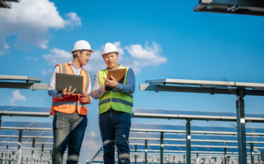 Two men in safety vests talking in the middle of a solar farm